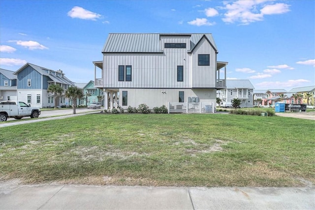 exterior space featuring a front yard, metal roof, board and batten siding, and a residential view