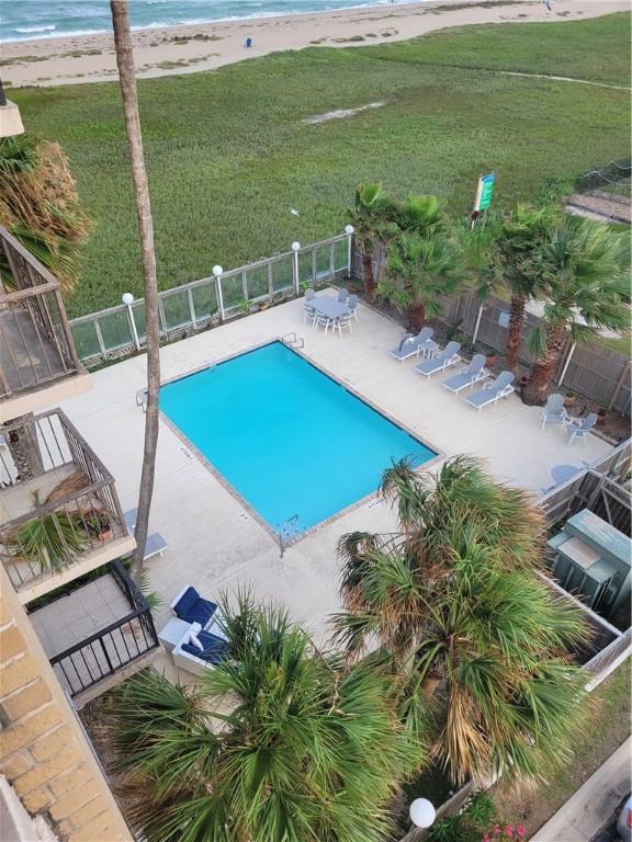 pool featuring a patio area, a beach view, a yard, and fence