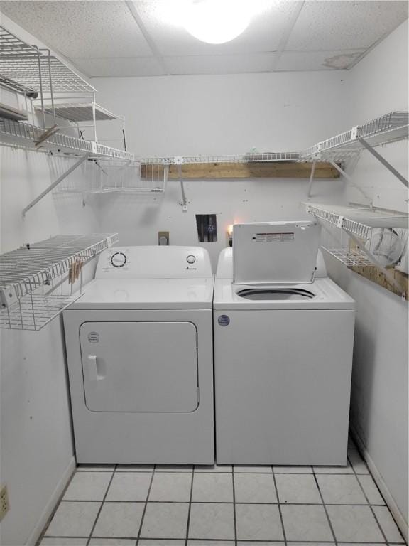 washroom with light tile patterned floors, laundry area, independent washer and dryer, and baseboards