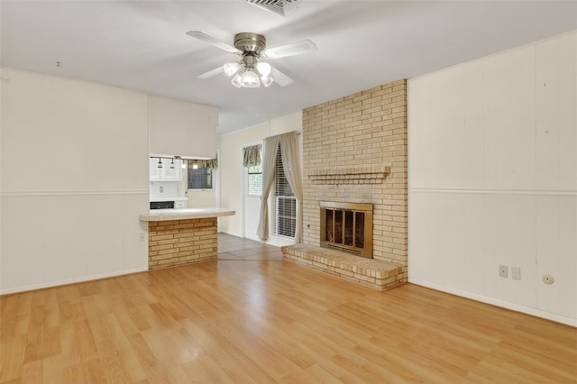4634 Bonner Dr, Corpus Christi, TX 78411 - unfurnished living room featuring light wood-type flooring, a ceiling fan, a brick fireplace, and a decorative wall