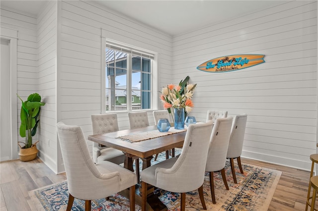 dining area with wooden walls and light hardwood / wood-style flooring