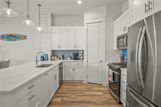 kitchen featuring white cabinets, hardwood / wood-style flooring, sink, backsplash, and appliances with stainless steel finishes