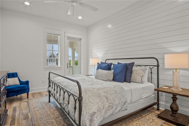 bedroom with wood walls, hardwood / wood-style flooring, and ceiling fan