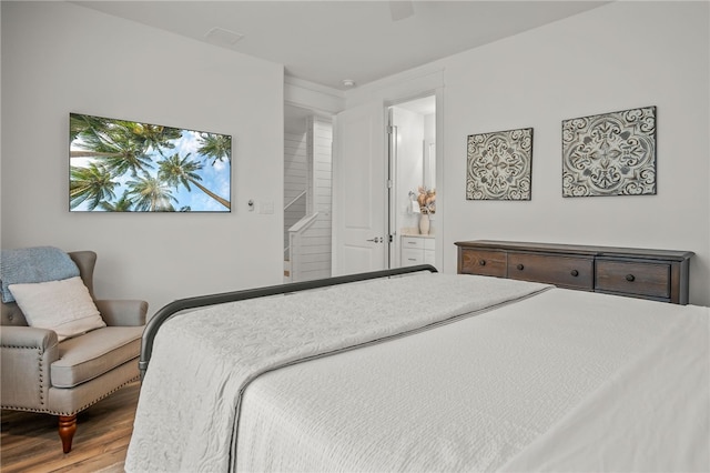 bedroom with wood-type flooring, ceiling fan, and ensuite bath