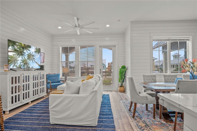 living room with hardwood / wood-style floors, wooden walls, and ceiling fan