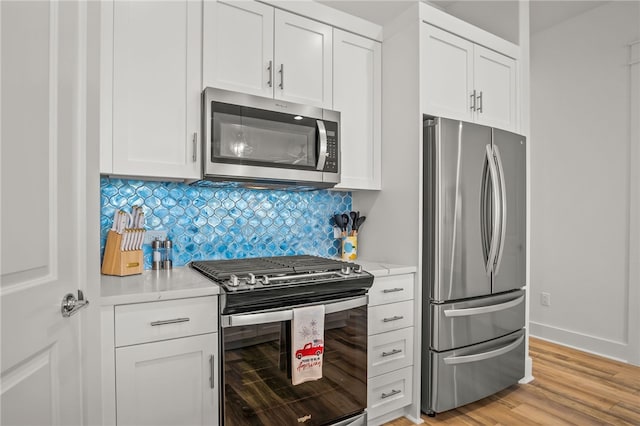 kitchen featuring tasteful backsplash, stainless steel appliances, white cabinetry, light stone countertops, and light hardwood / wood-style flooring