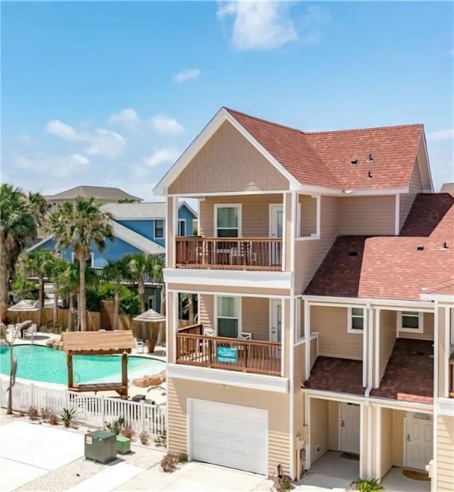 back of house with a fenced in pool, a balcony, and a garage