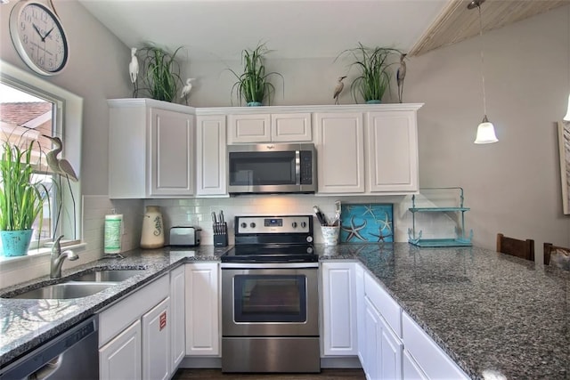 kitchen featuring sink, white cabinetry, dark stone counters, stainless steel appliances, and backsplash