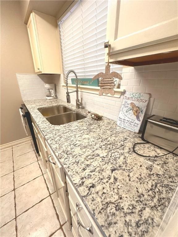 kitchen featuring decorative backsplash, light stone counters, and sink