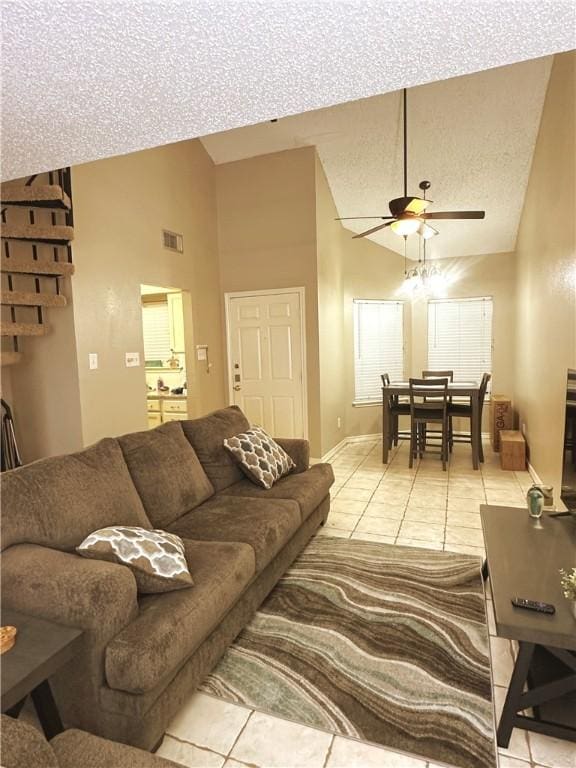 tiled living room with ceiling fan, high vaulted ceiling, and a textured ceiling