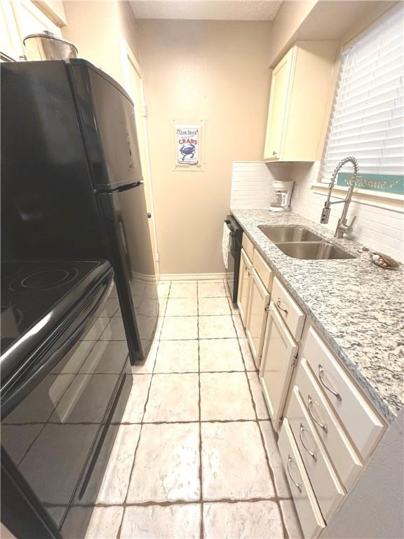 kitchen with backsplash, light stone counters, sink, and light tile patterned floors