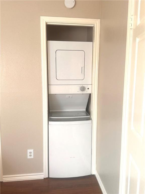 laundry room with stacked washer and dryer and dark wood-type flooring