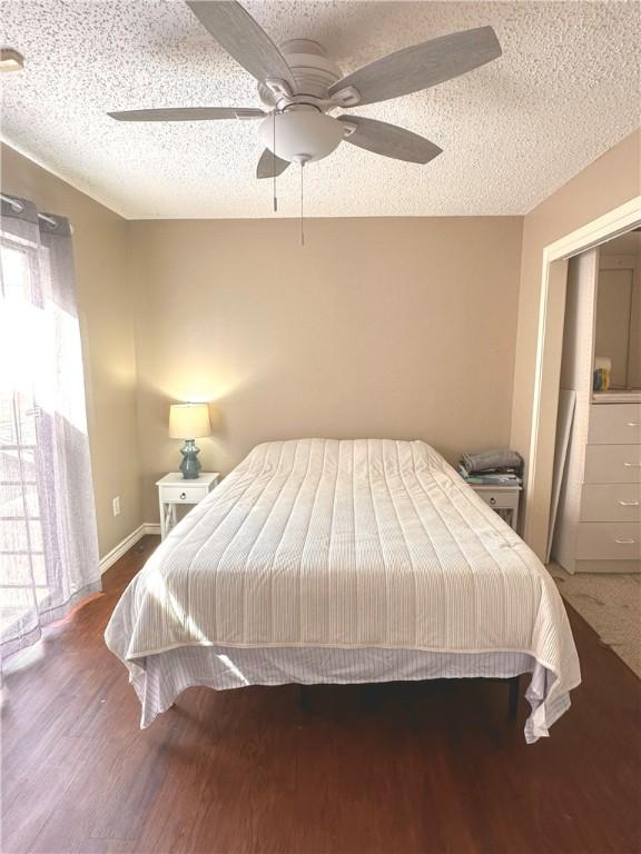 bedroom with a textured ceiling, ceiling fan, and dark wood-type flooring