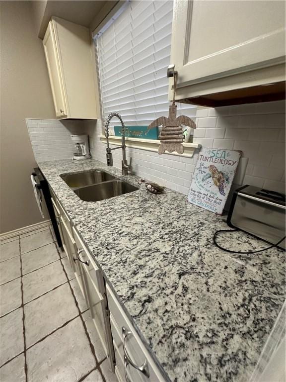 kitchen with backsplash, white cabinets, sink, light tile patterned floors, and light stone counters