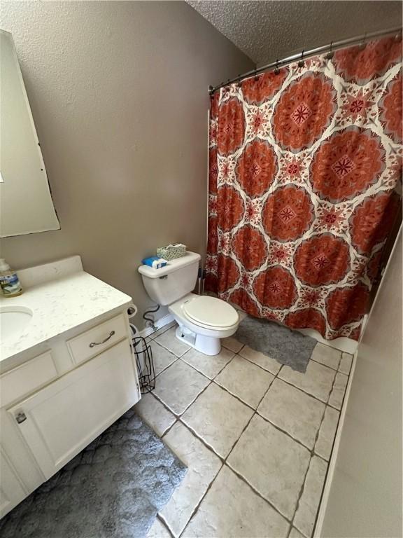 bathroom with tile patterned floors, vanity, toilet, and a textured ceiling