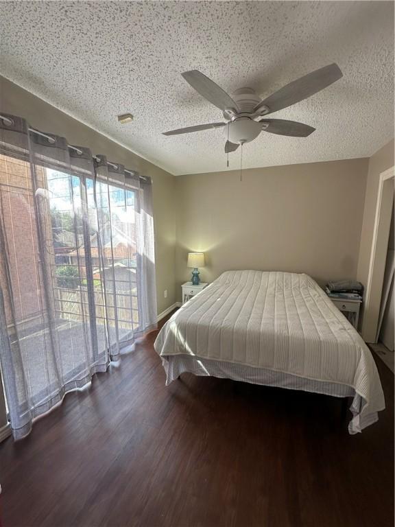 bedroom with access to outside, ceiling fan, dark wood-type flooring, and a textured ceiling