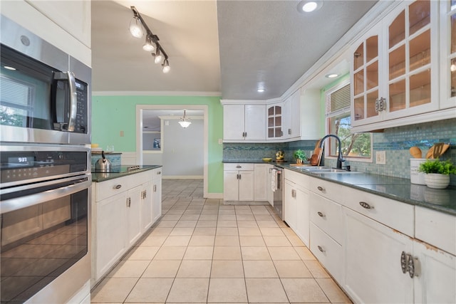 kitchen with appliances with stainless steel finishes, glass insert cabinets, and white cabinets