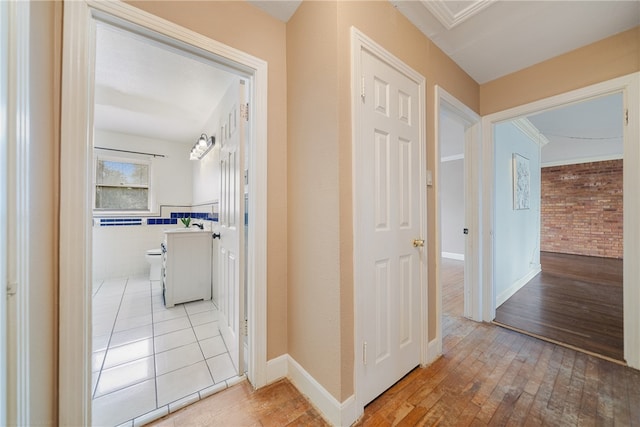 hallway with light wood finished floors and tile walls