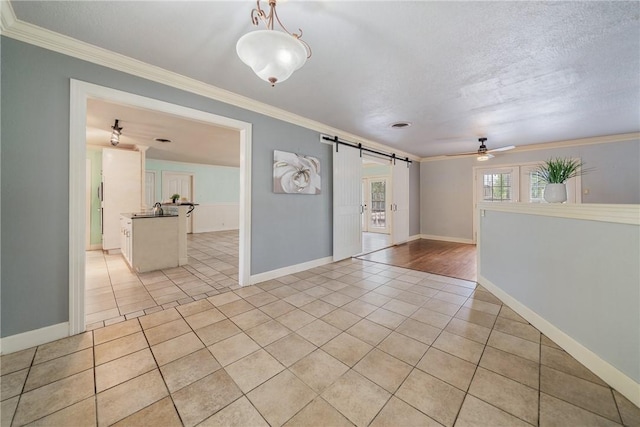 unfurnished room featuring light tile patterned floors, crown molding, a textured ceiling, and a barn door