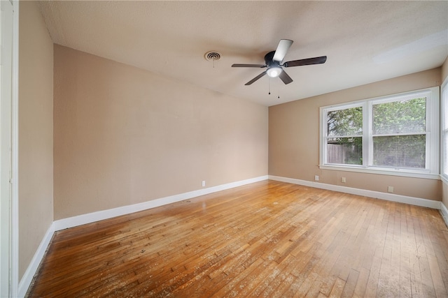 empty room featuring baseboards, a ceiling fan, visible vents, and light wood-style floors