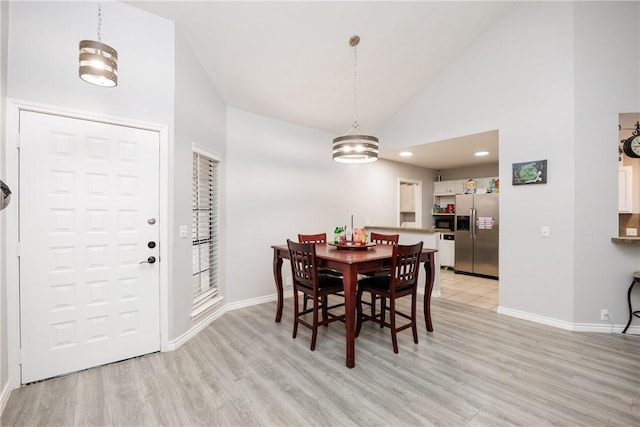 dining room with high vaulted ceiling and light wood-type flooring