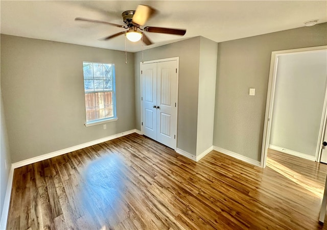 unfurnished bedroom with wood-type flooring, a closet, and ceiling fan