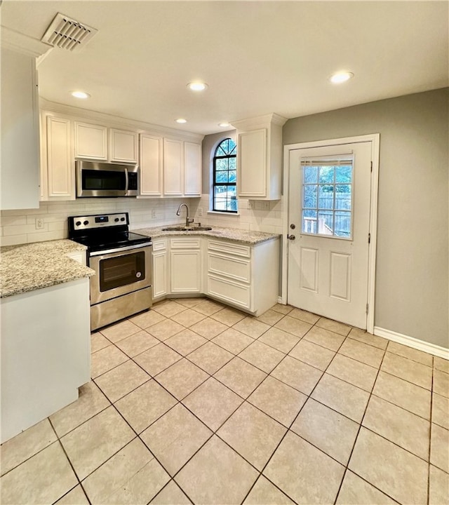 kitchen with white cabinets, light stone counters, sink, and appliances with stainless steel finishes