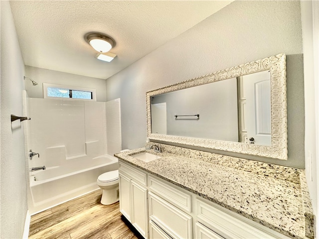 full bathroom with vanity, a textured ceiling, bathing tub / shower combination, hardwood / wood-style flooring, and toilet