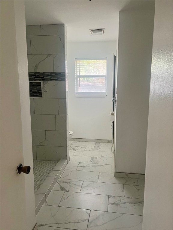 bathroom featuring toilet and a tile shower