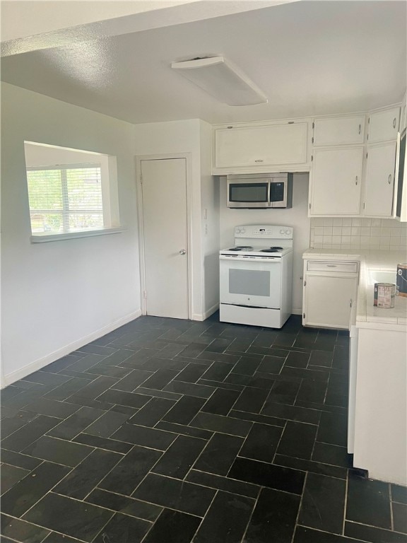 kitchen featuring white cabinets, tasteful backsplash, and electric range