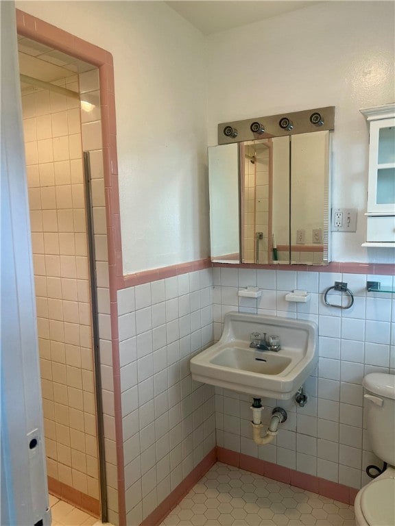 bathroom with sink, tile patterned floors, toilet, and tile walls