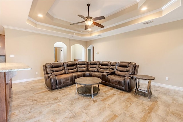 living room with crown molding, a raised ceiling, a ceiling fan, and arched walkways