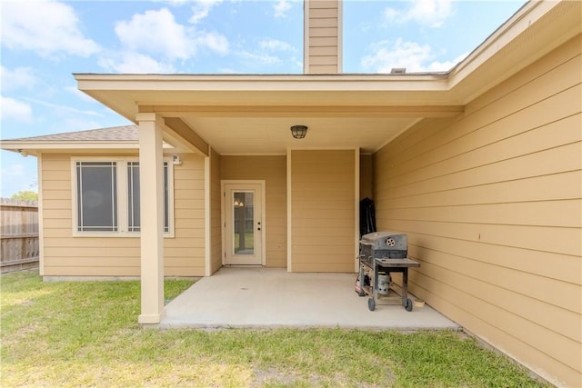 entrance to property with a yard, fence, a chimney, and a patio area