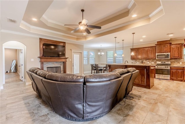 living area featuring ceiling fan, visible vents, ornamental molding, and a tray ceiling