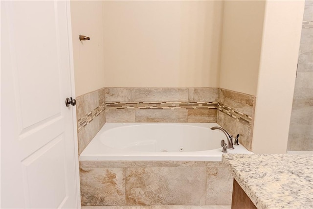 bathroom with a tub with jets and vanity
