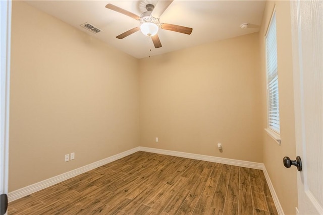 spare room featuring visible vents, a ceiling fan, baseboards, and wood finished floors