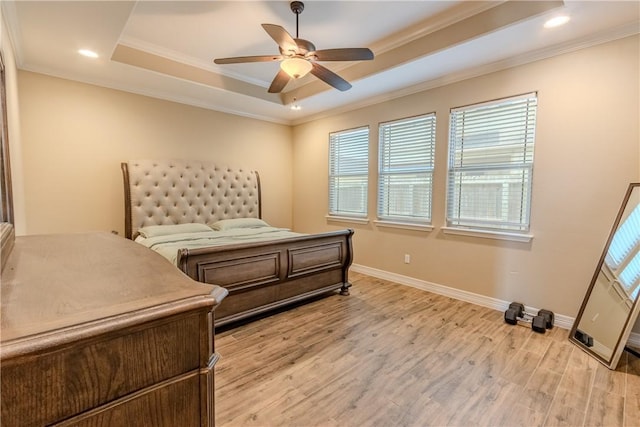 bedroom featuring baseboards, ornamental molding, a tray ceiling, and light wood finished floors