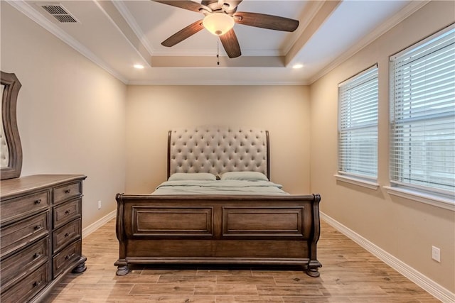bedroom with ceiling fan, light wood-style floors, baseboards, a tray ceiling, and visible vents