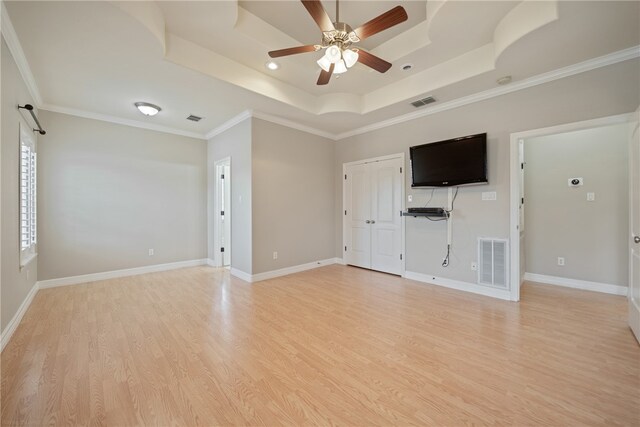 unfurnished living room featuring ornamental molding, ceiling fan, a tray ceiling, and light hardwood / wood-style floors