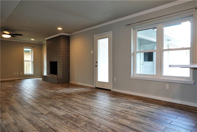 unfurnished living room with ceiling fan, wood-type flooring, ornamental molding, and a brick fireplace