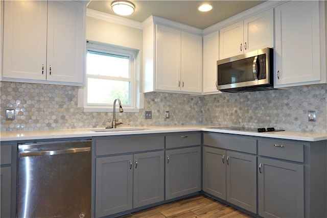 kitchen featuring gray cabinets, crown molding, stainless steel appliances, and tasteful backsplash