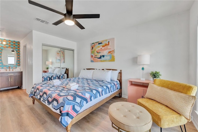 bedroom featuring ceiling fan, wood-type flooring, ensuite bathroom, and a closet