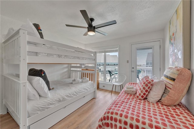 bedroom with access to outside, ceiling fan, light hardwood / wood-style floors, and a textured ceiling