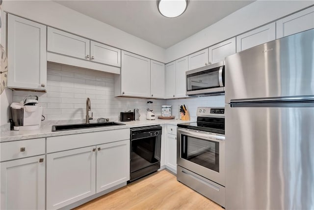 kitchen with white cabinets, sink, stainless steel appliances, and light hardwood / wood-style flooring