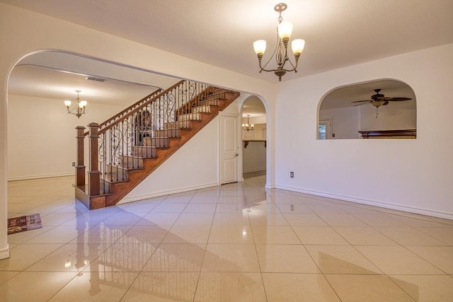 tiled empty room featuring ceiling fan with notable chandelier