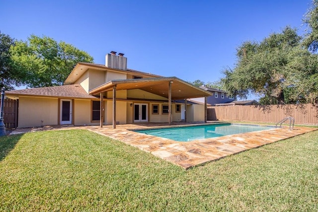 rear view of house with a fenced in pool, a patio, and a lawn