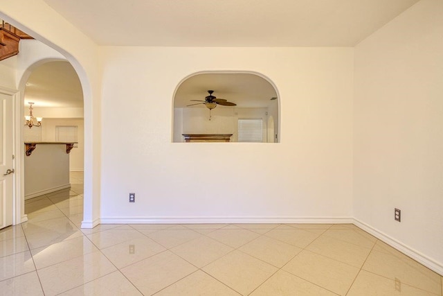 tiled spare room with ceiling fan with notable chandelier