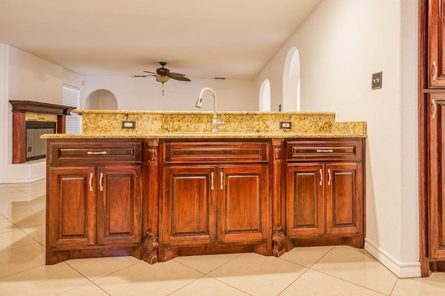 kitchen with light stone countertops, ceiling fan, light tile patterned floors, and kitchen peninsula