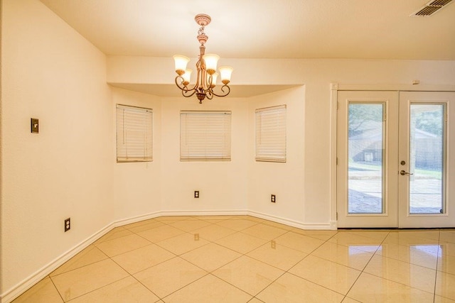 unfurnished dining area featuring french doors, a notable chandelier, and light tile patterned floors