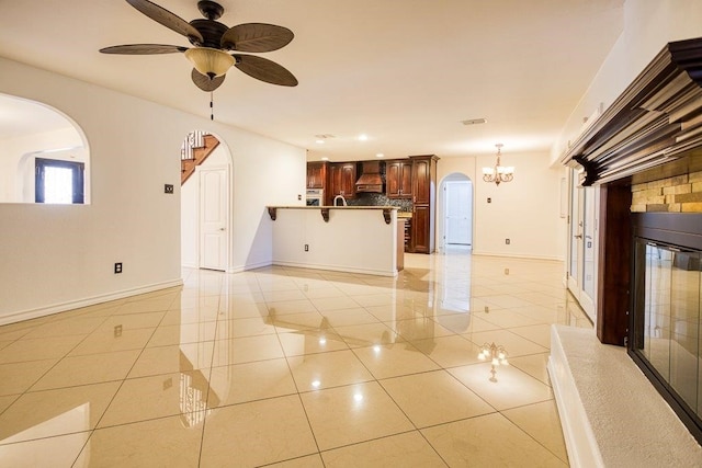 unfurnished living room featuring ceiling fan with notable chandelier, light tile patterned floors, and sink